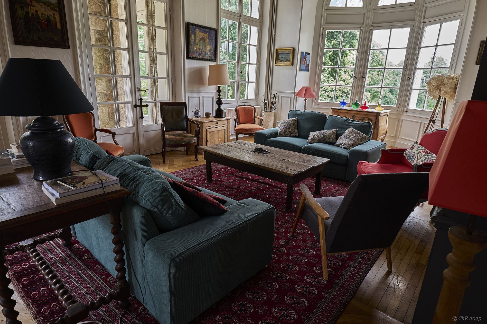 Le grand salon et ses hautes fenêtres cintrées ouvertes sur le parc